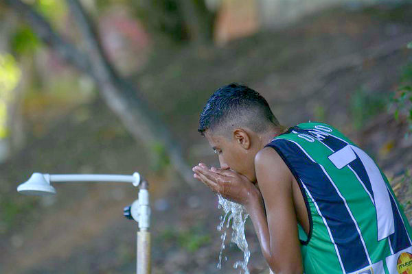 Alguns jovens até improvisam um jeito para matar a sede. Sem vestiários ou bebedouros fixos, o jeito é tomar água de um cano de um dos chuveiros quebrados (Foto: Antonio Lima)